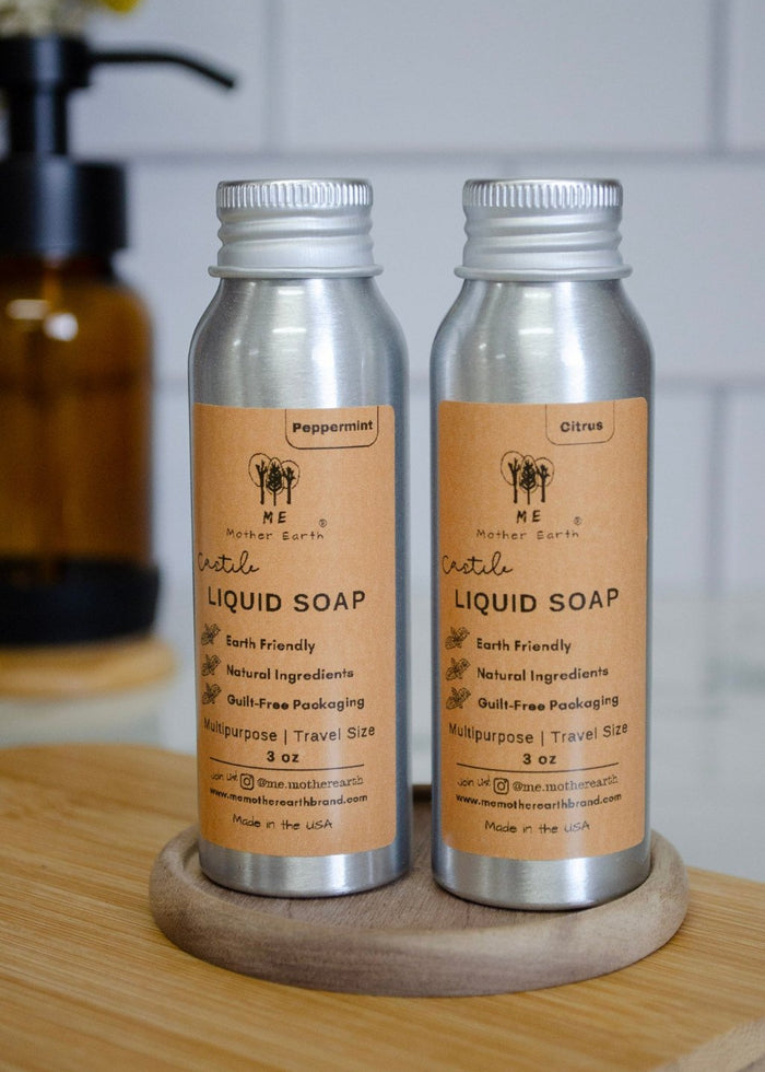 Two bottles of liquid castile soap on a wooden stand with a white tiled wall background.
