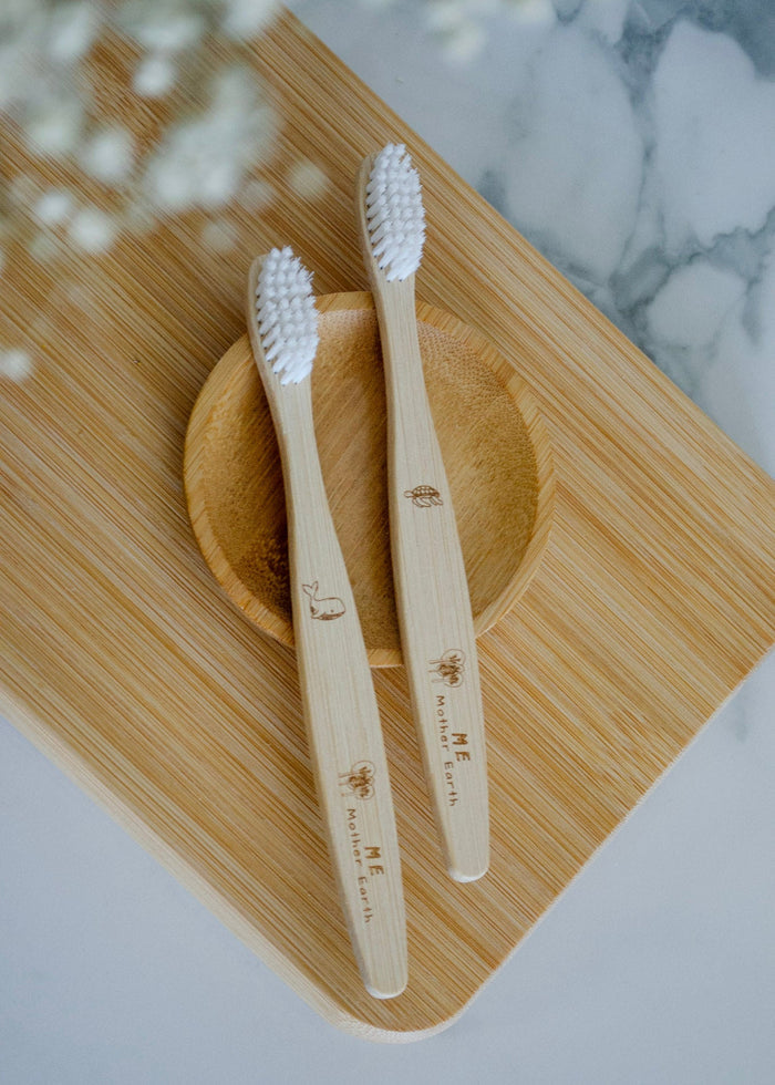 Two bamboo toothbrushes on a wooden stand with a marble background