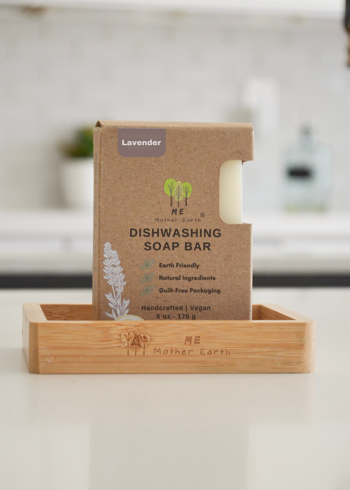 Lavender Dishwashing soap bar in a cardboard packaging on a wooden stand with a blurred kitchen background.