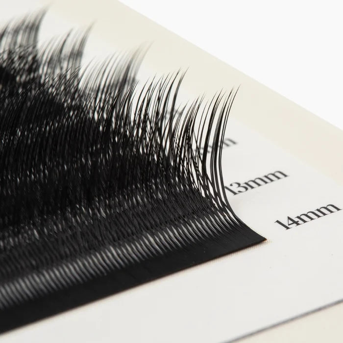 Macro close-up of black Kitten Lash extension fibres on a lash strip, showing the curl and length markings.