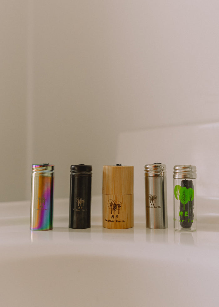 Five cylindrical containers with different designs on a white surface next to a faucet.