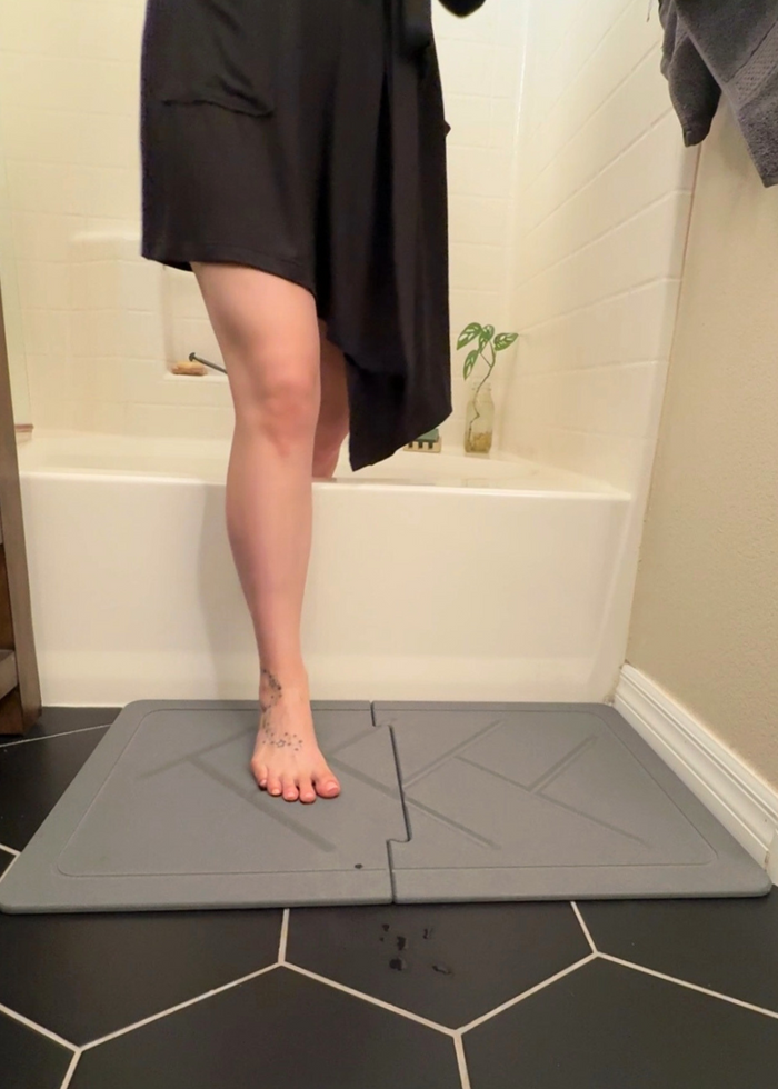 Person standing on a gray Stone mat in a bathroom
